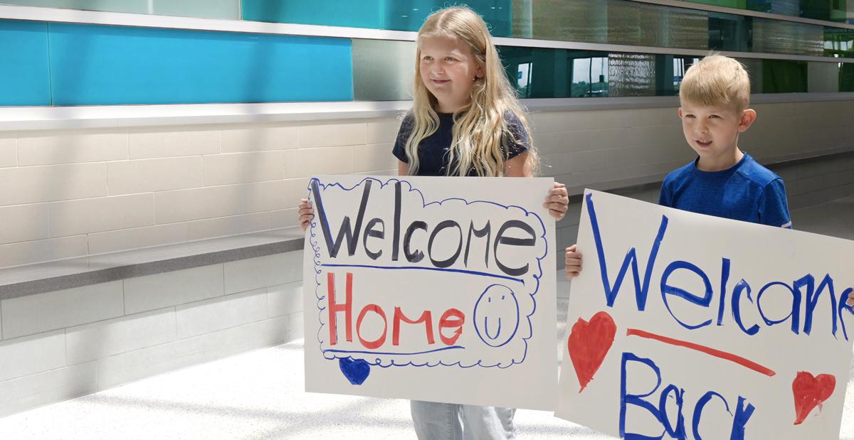 kids with welcome home signs